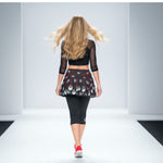Load image into Gallery viewer, Woman walking on a runway wearing a black top and patterned skirt.

