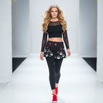 Load image into Gallery viewer, Model walking on a runway wearing a black outfit with festive designs.
