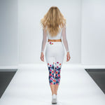 Load image into Gallery viewer, Woman walking on a runway wearing a white outfit with colorful floral leggings.
