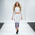 Load image into Gallery viewer, Woman wearing a white athletic outfit with floral leggings on a runway.
