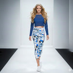 Load image into Gallery viewer, Model walking on a runway wearing a blue top and patterned leggings.

